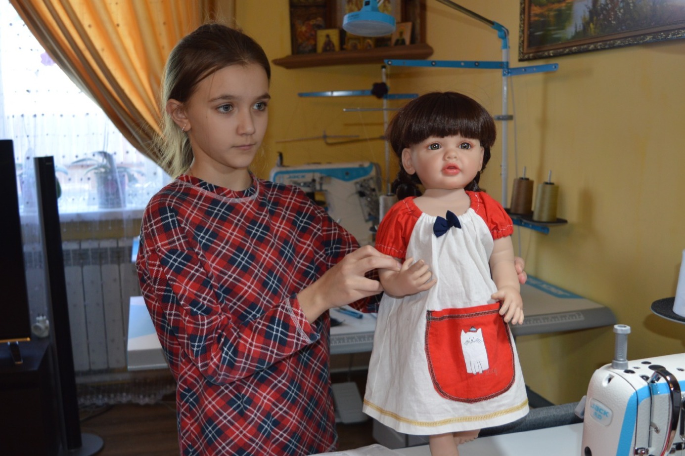 Дочка Маша показывает куклу в платье, сшитом вместе с сестрёнкой