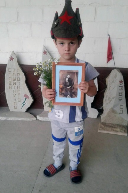 Юный житель станицы Калиновская с портретом супругов Казаковых